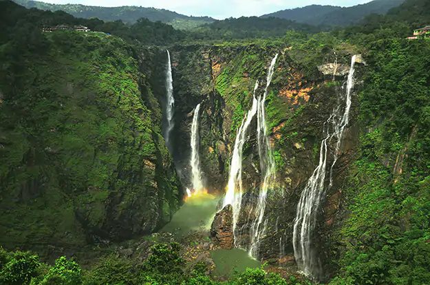 Photo of a waterfall with lush greenery and a rainbow